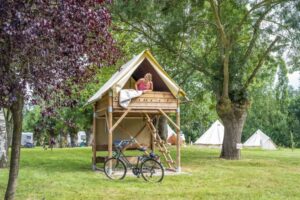 Une femme dans un bivouac sur piloti du camping EcoLoire