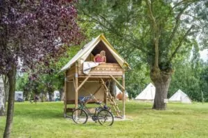 Une femme dans un bivouac sur piloti du camping EcoLoire