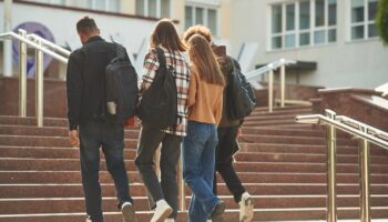 Un groupe d'étudiants montent les marches de leur établissement scolaire