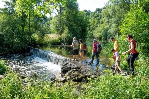 Des randonneurs traversent un petit barrage d'eau