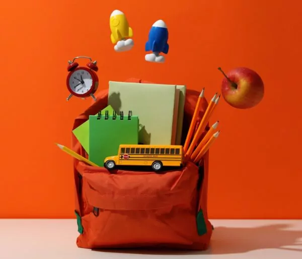 Fournitures scolaires dans un sac à dos sur fond orange.