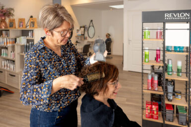 Une employée du salon de coiffure l'Art de Pl'Hair coiffe une cliente
