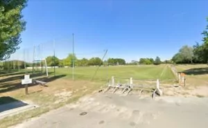 vue d'ensemble du stade des echuettes au Mesnil-en-Vallée. La pelouse est verte et le ciel est bleu
