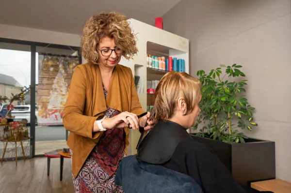 Une coiffeuse de L'Coiff fait une coupe de cheveux à une cliente