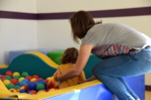Une enfant dans une piscine à balle. Sa maman la retient