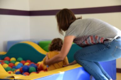 Une enfant dans une piscine à balle. Sa maman la retient