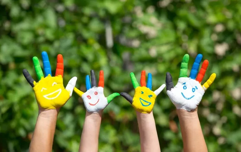 Mains d'enfants et d'adultes colorées et peintes avec des visages avec le sourire. Relais Petite Enfance