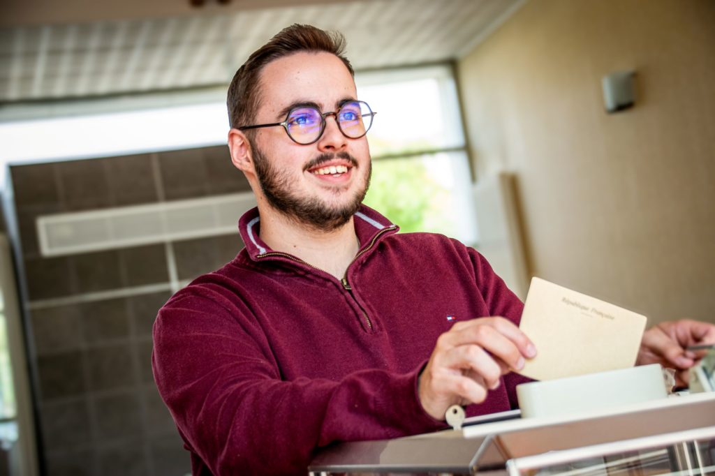 ©Bourget_Axel_Mairie_de_Mauges_sur_Loire_Elections_2025_09_25-2 personne jeune souriante avec un pull bordeaux qui vote