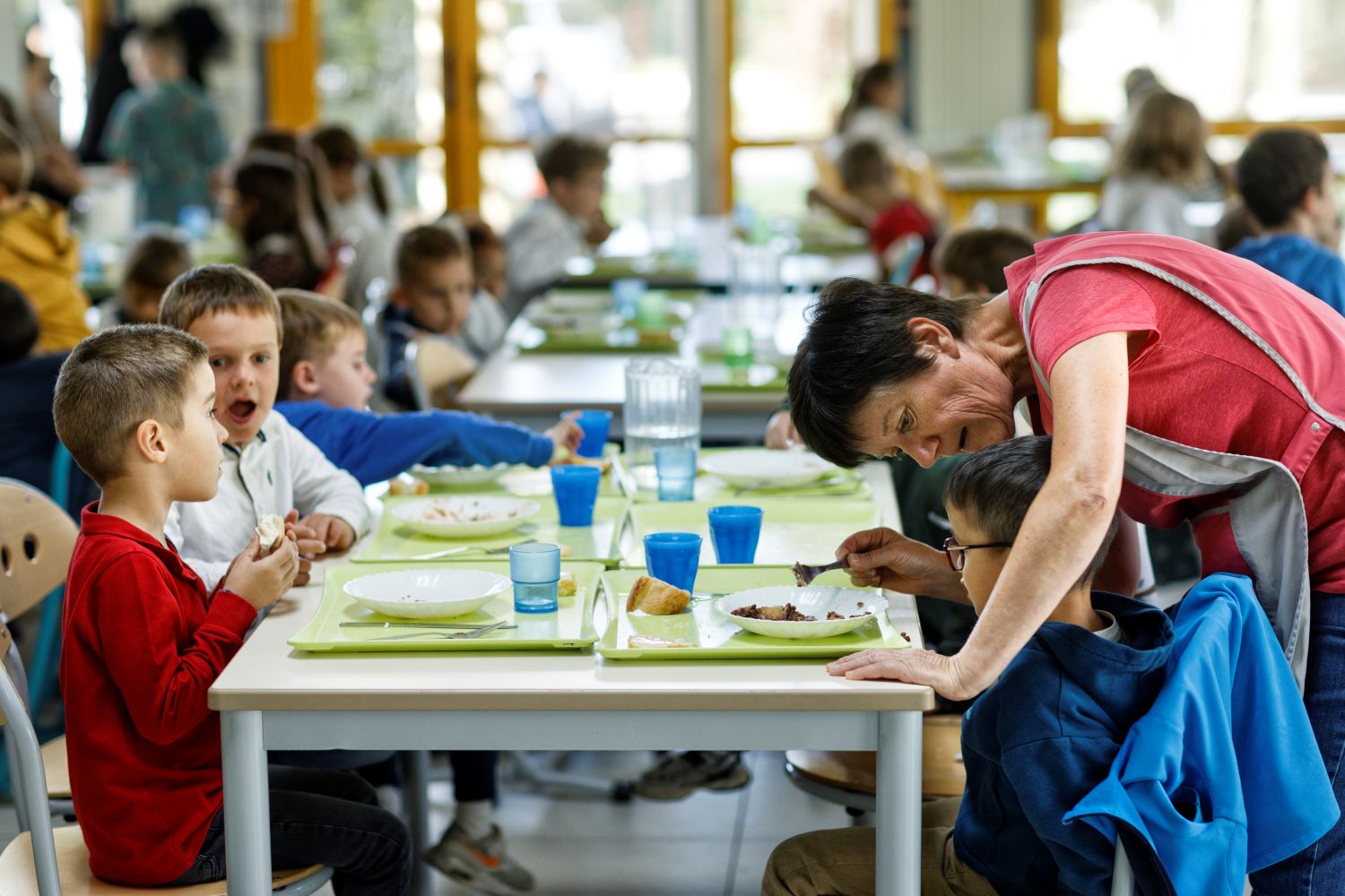 Dans un restaurant scolaire des enfants sont assis à table