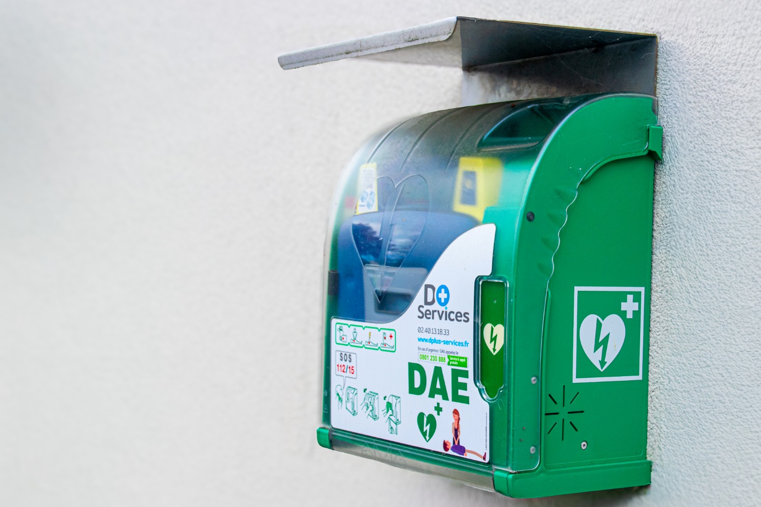 défibrillateur accroché sur un mur blanc