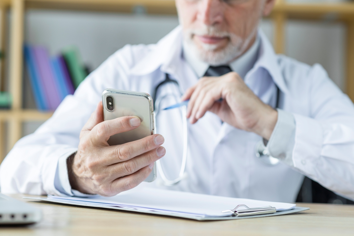Médecin dans son cabinet qui tient un téléphone dans sa main