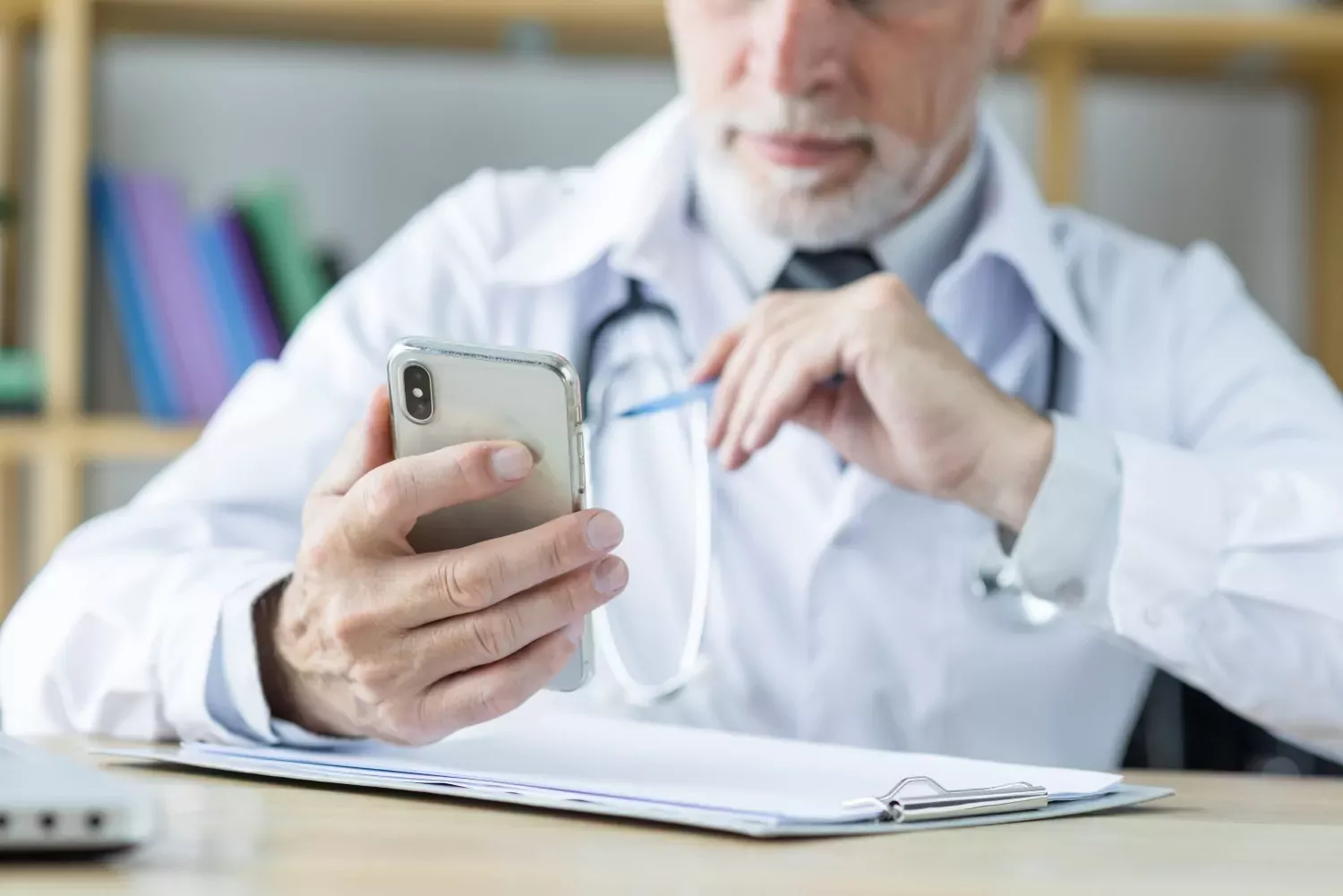 Médecin dans son cabinet qui tient un téléphone dans sa main