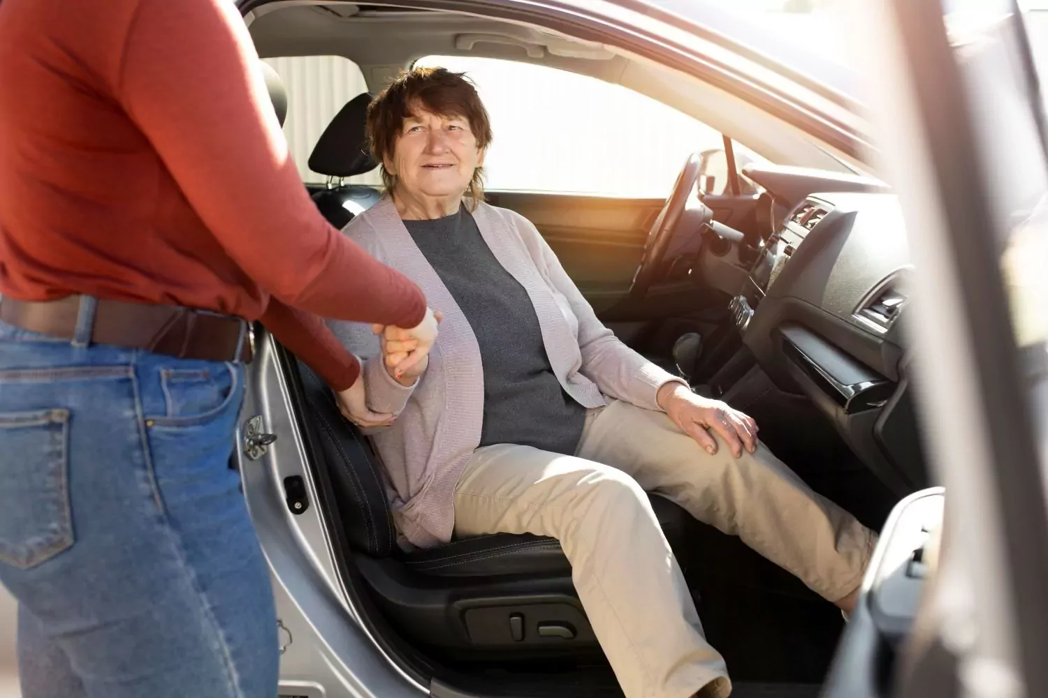 une personne aide une personne agée à descendre d'une voiture