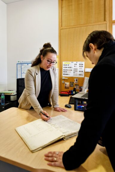2 personnes dans un bureau regardant des registres d'état civils
