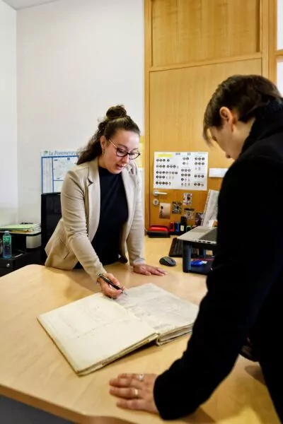 2 personnes dans un bureau regardant des registres d'état civils
