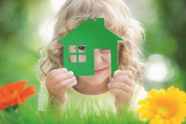 Petite fille qui tient une maison verte dans ses mains