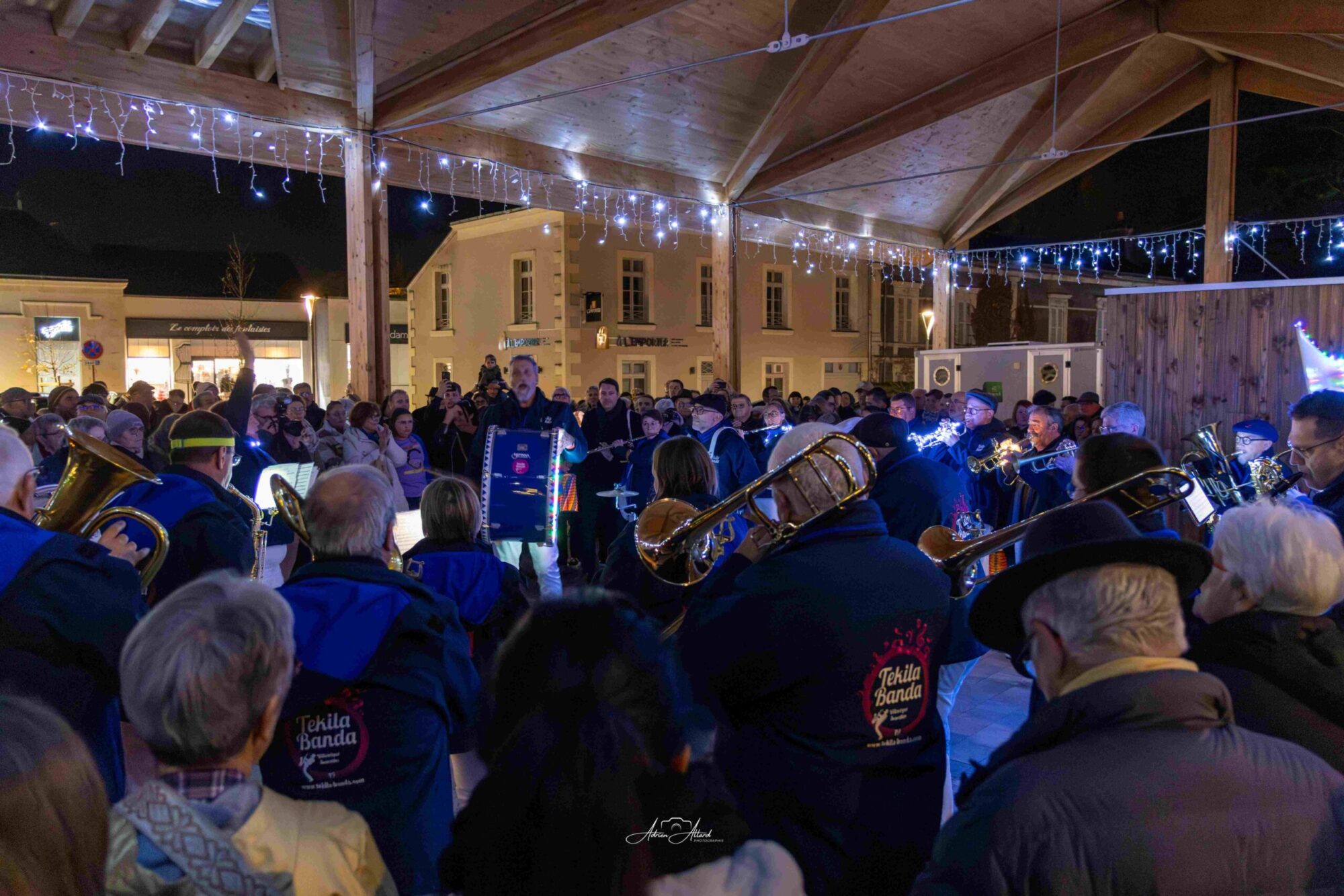 Petites Cités d'Anjou en Lumière 2025 sous la halle de la place de la Févrière avec beaucoup de personnes