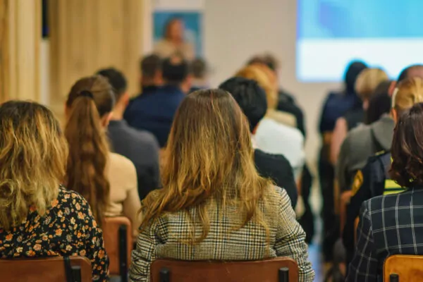 Réunion avec des personnes assises vu de dos regardant une projection