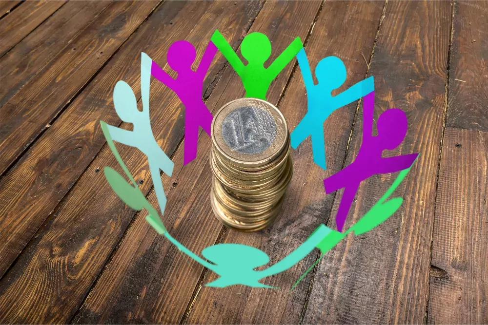Photo d'une farandole de personnes en papier entourant des pièces de 1€ empilées